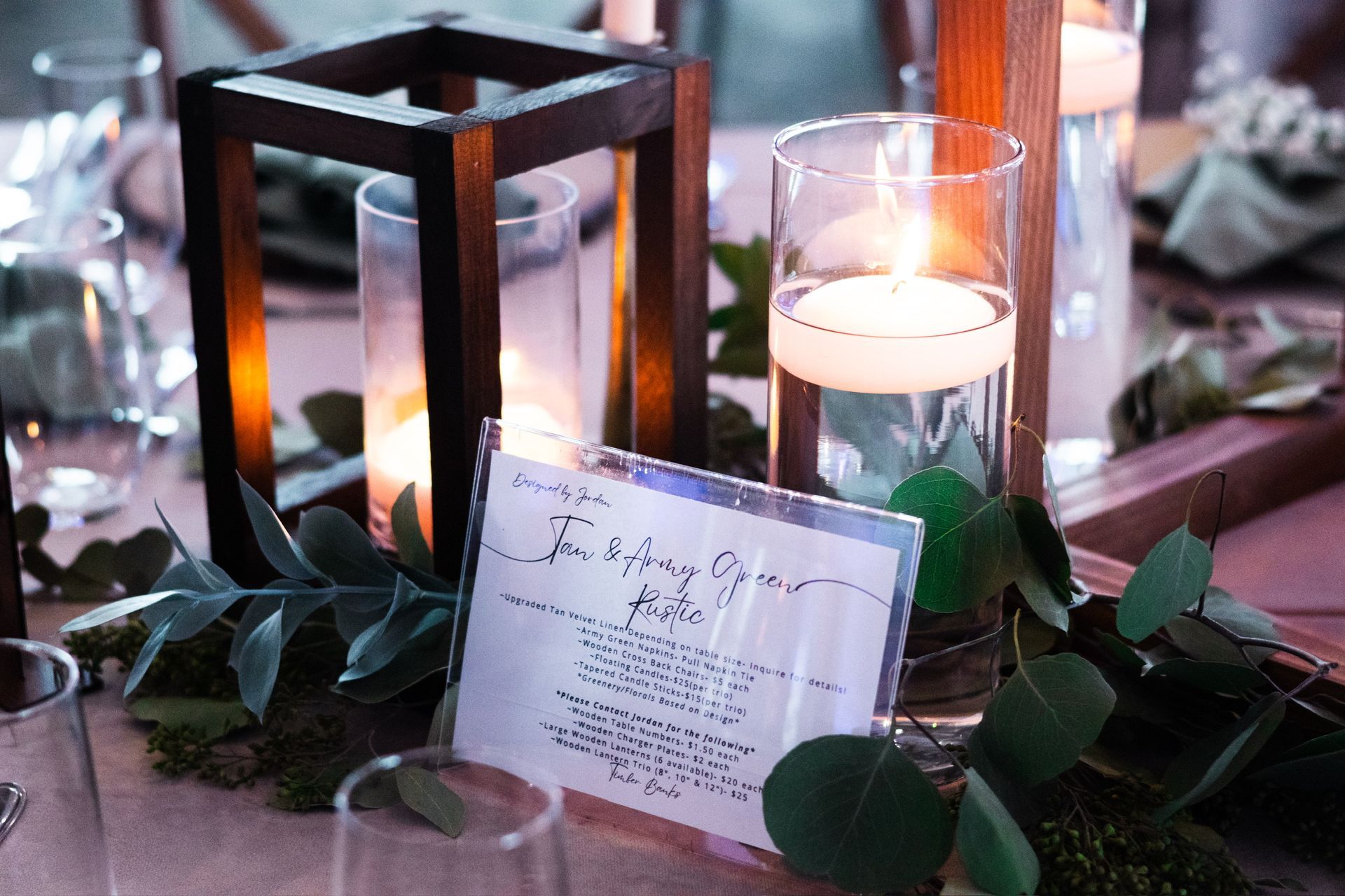 Wedding table centerpiece with wooden lantern, floating candle, menu, greenery.