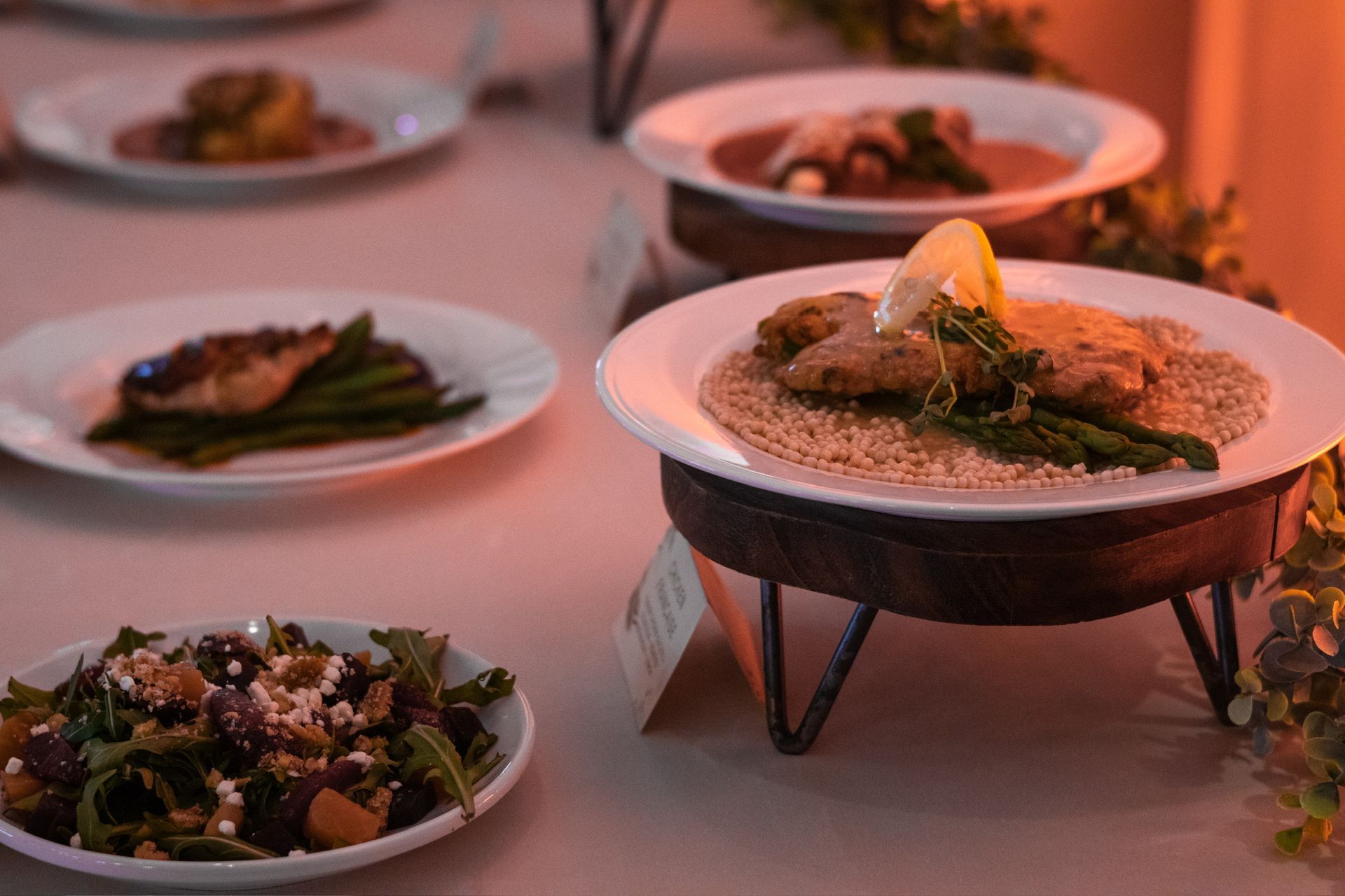 Plated food at a wedding or event, including salad, fish, and garnishes.