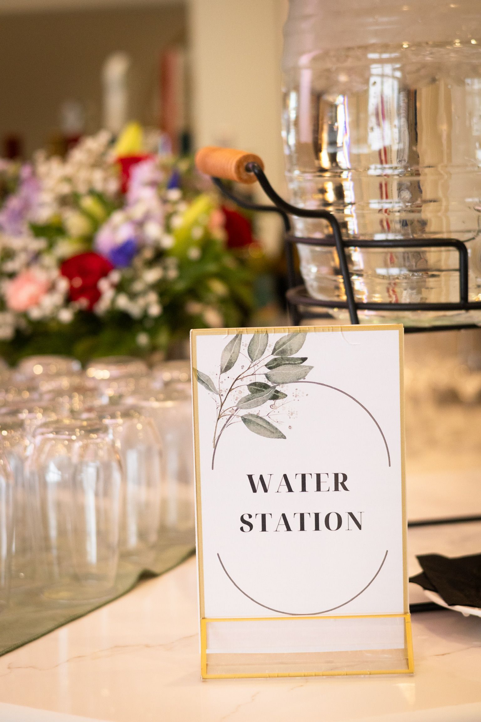 Water station sign on a table, with water dispenser and glasses.