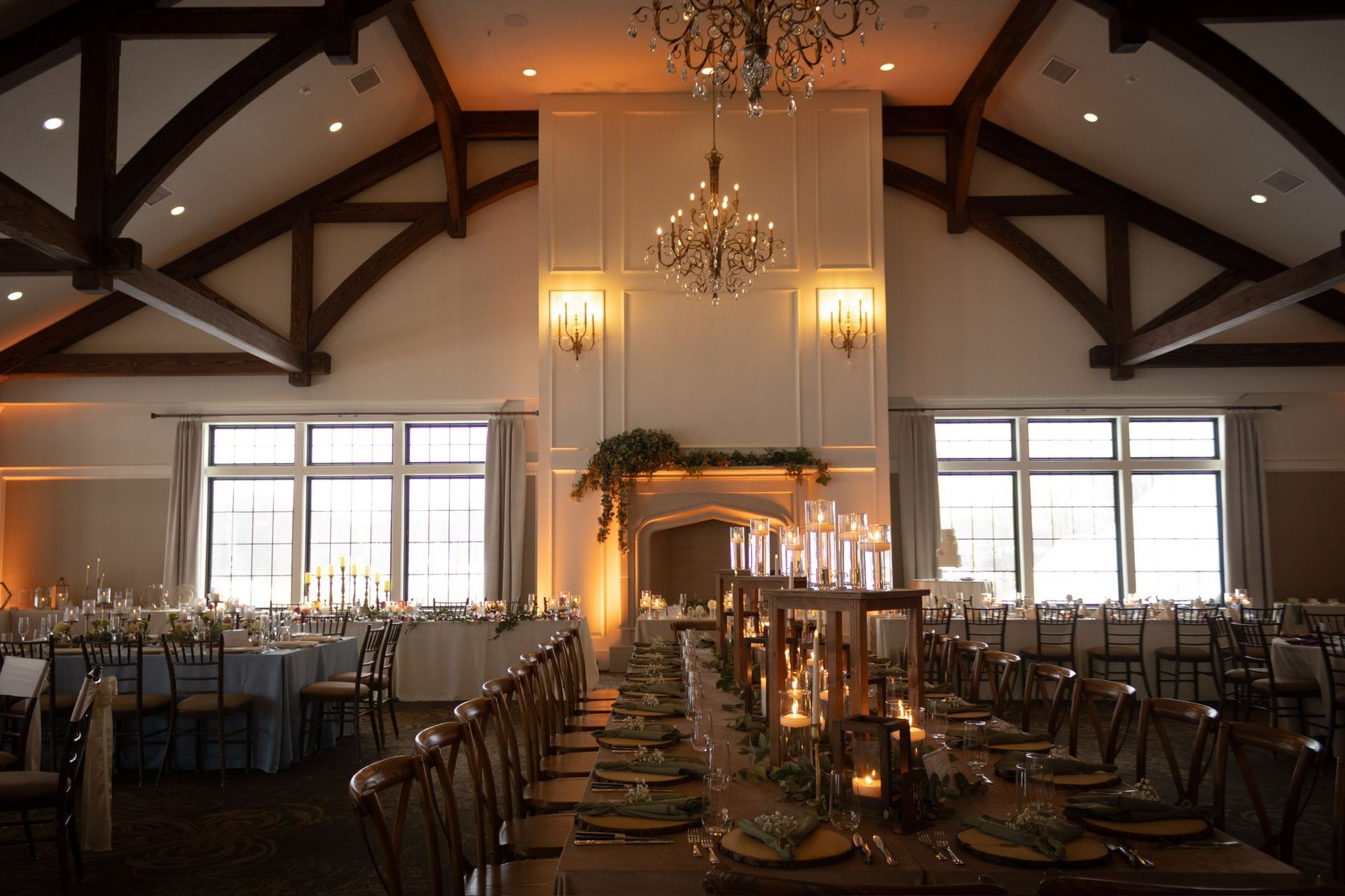 Elegant banquet hall set up for a wedding reception, with long tables, candles, and a fireplace.