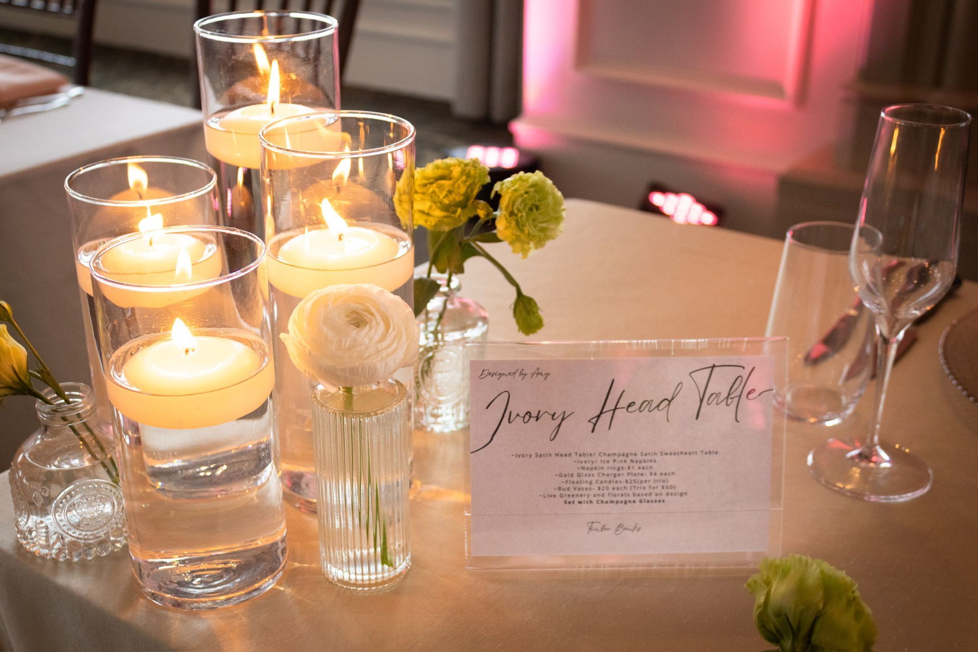 Table setting with floating candles, flowers, and a sign that reads 