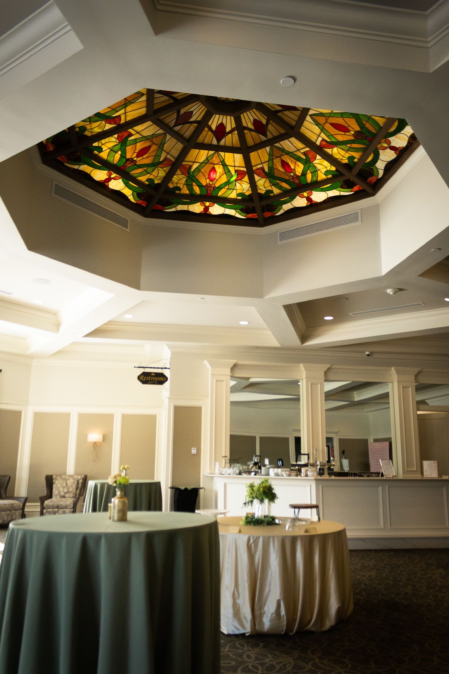 Interior view of a venue with tables, a decorative ceiling, and a bar area.
