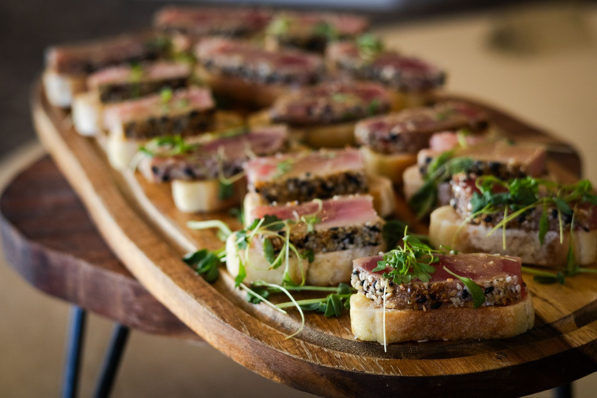 Tuna crostini appetizers on a wooden serving board, garnished with greens.