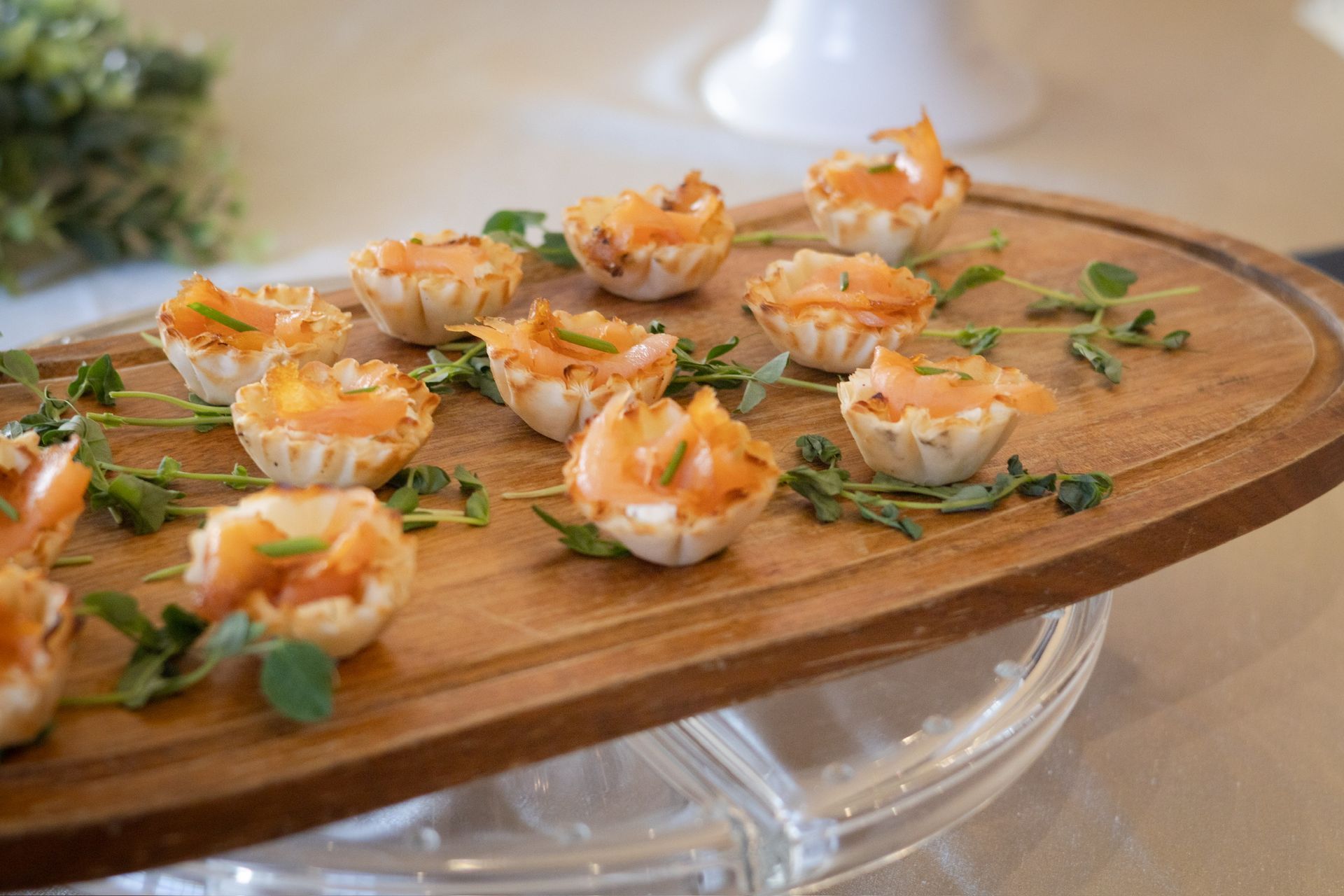 Smoked salmon tartlets on a wooden board, garnished with herbs.