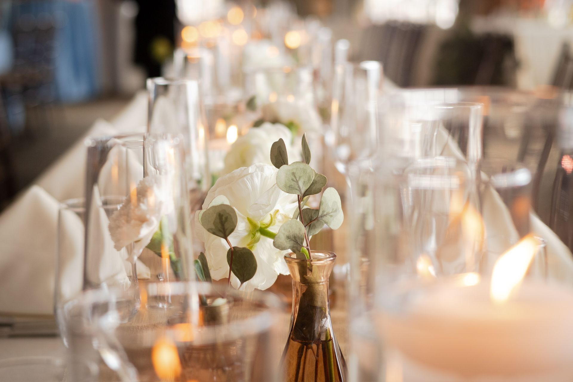 Table setting with white flowers, candles, and glassware.