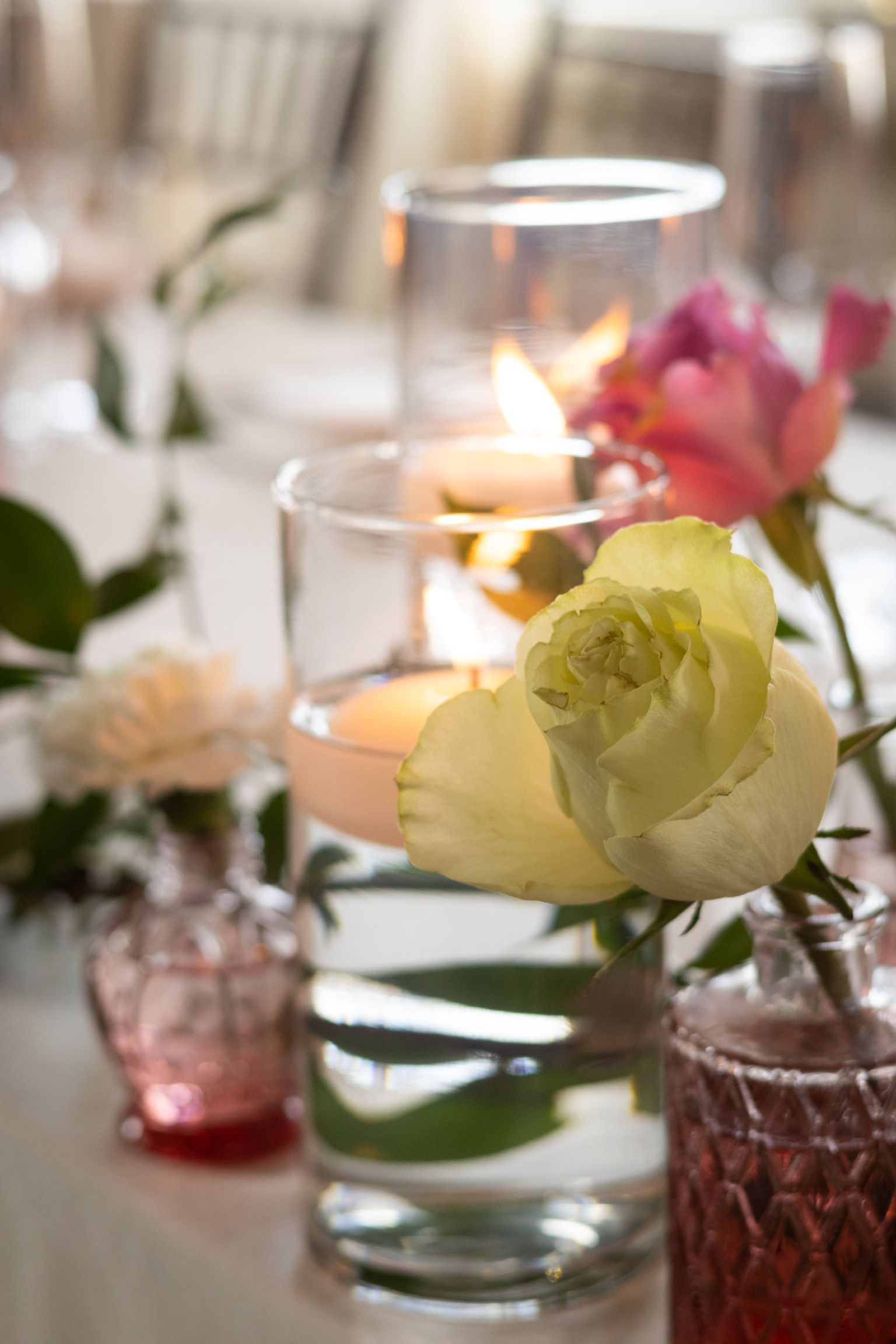 Table centerpiece with floating candles and flowers in glass vases.