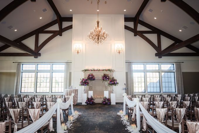 Elegant indoor wedding ceremony setup with draped aisle and floral fireplace.