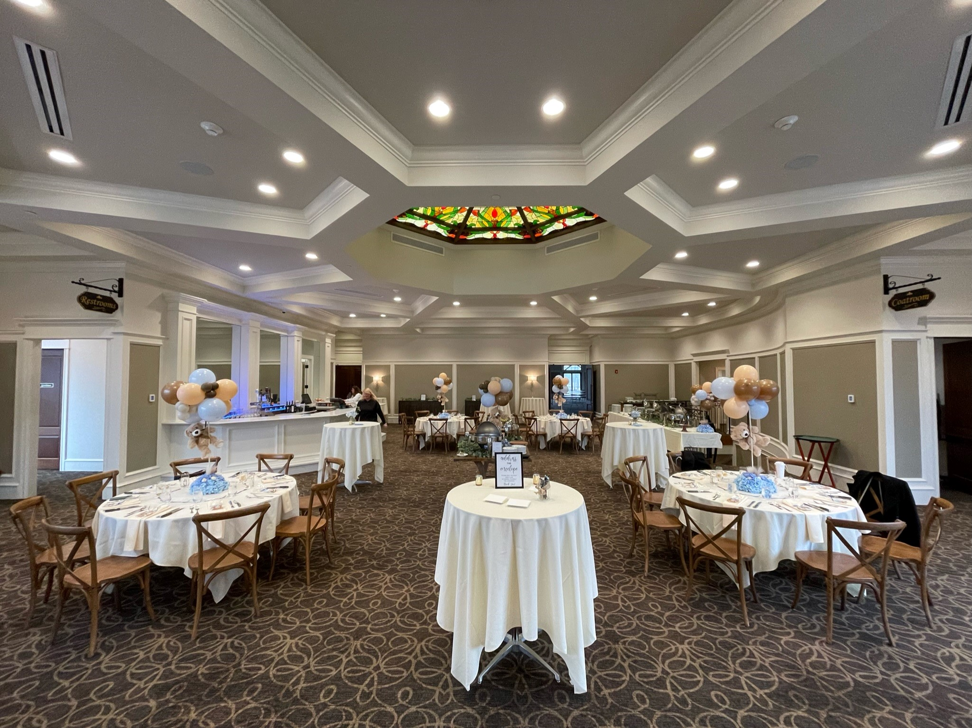 A large room with tables and chairs set up for a wedding reception.