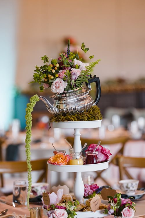 A three tiered cake stand with a teapot on top of it.