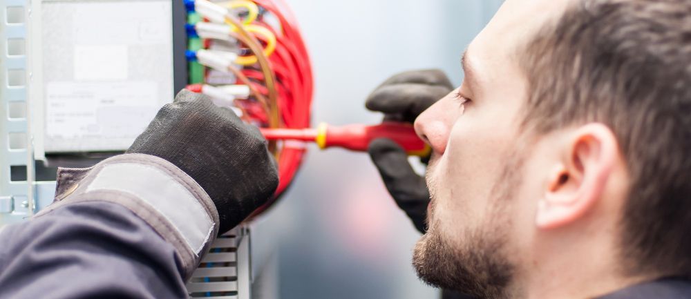 Man Is Working On An Electrical Box With A Screwdriver — Mingleford Electrical Airconditioning Solar & Gas In Baringa, QLD