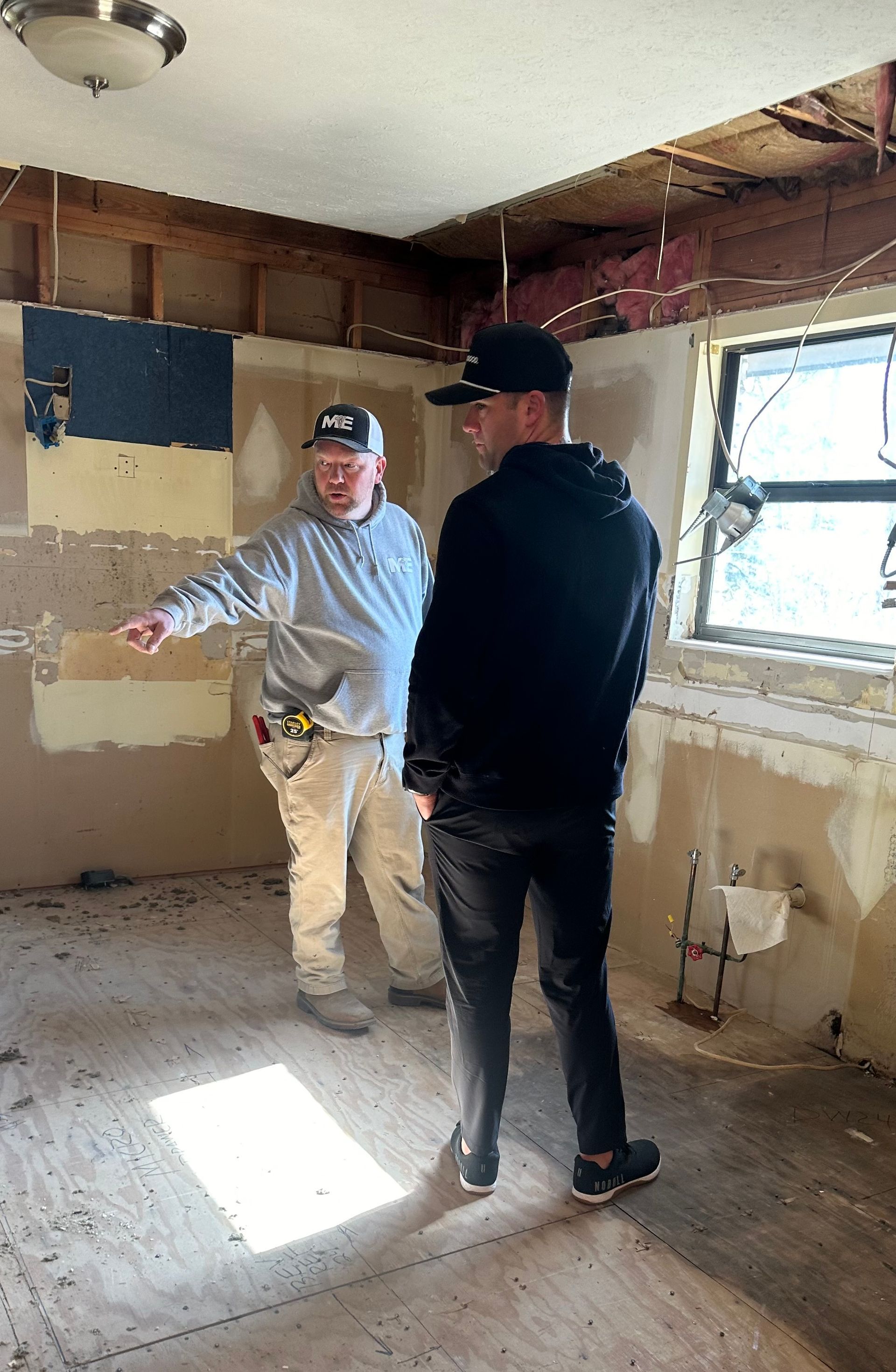 Two electricians standing in a room talking to each other.