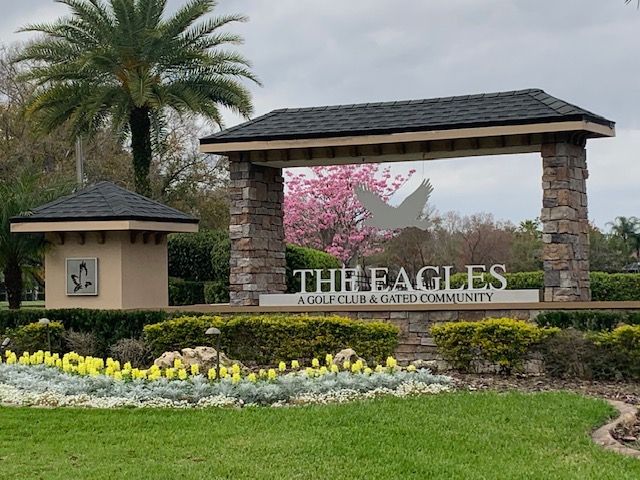 A large building with a blue roof is surrounded by grass and trees.