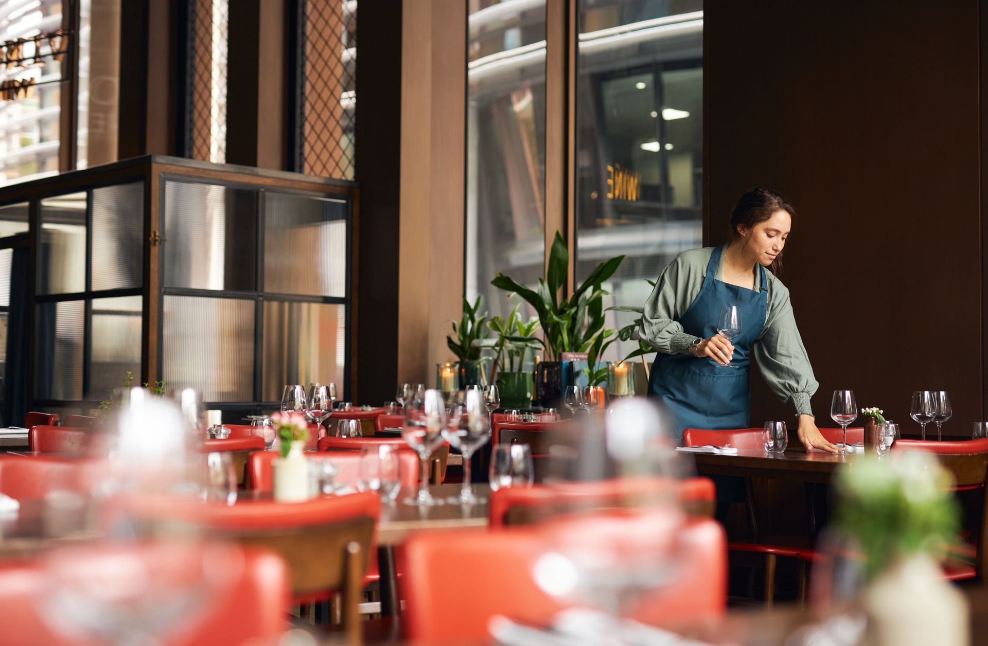 A woman is standing in a restaurant behind a table.