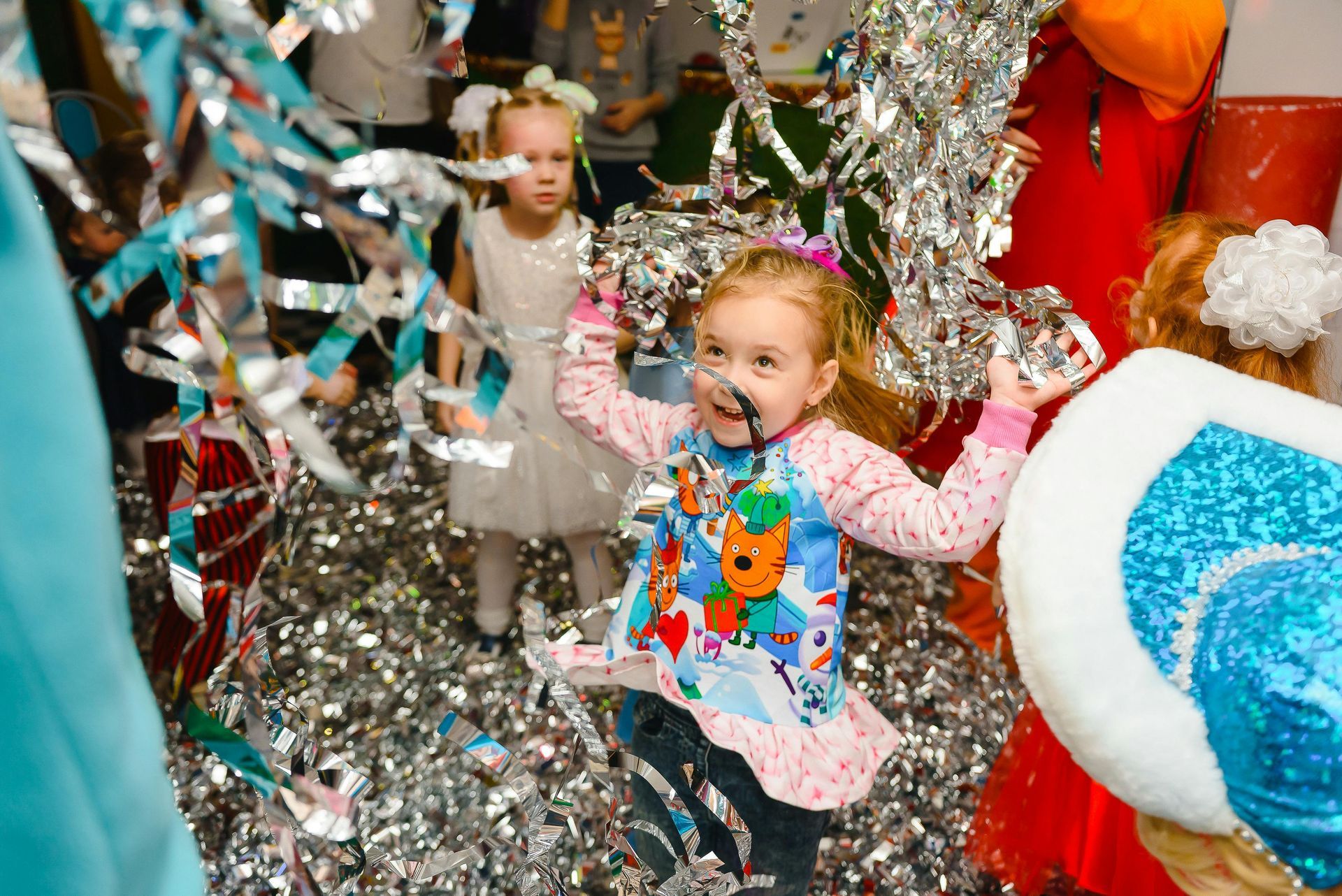 A little girl is playing with tinsel at a party.