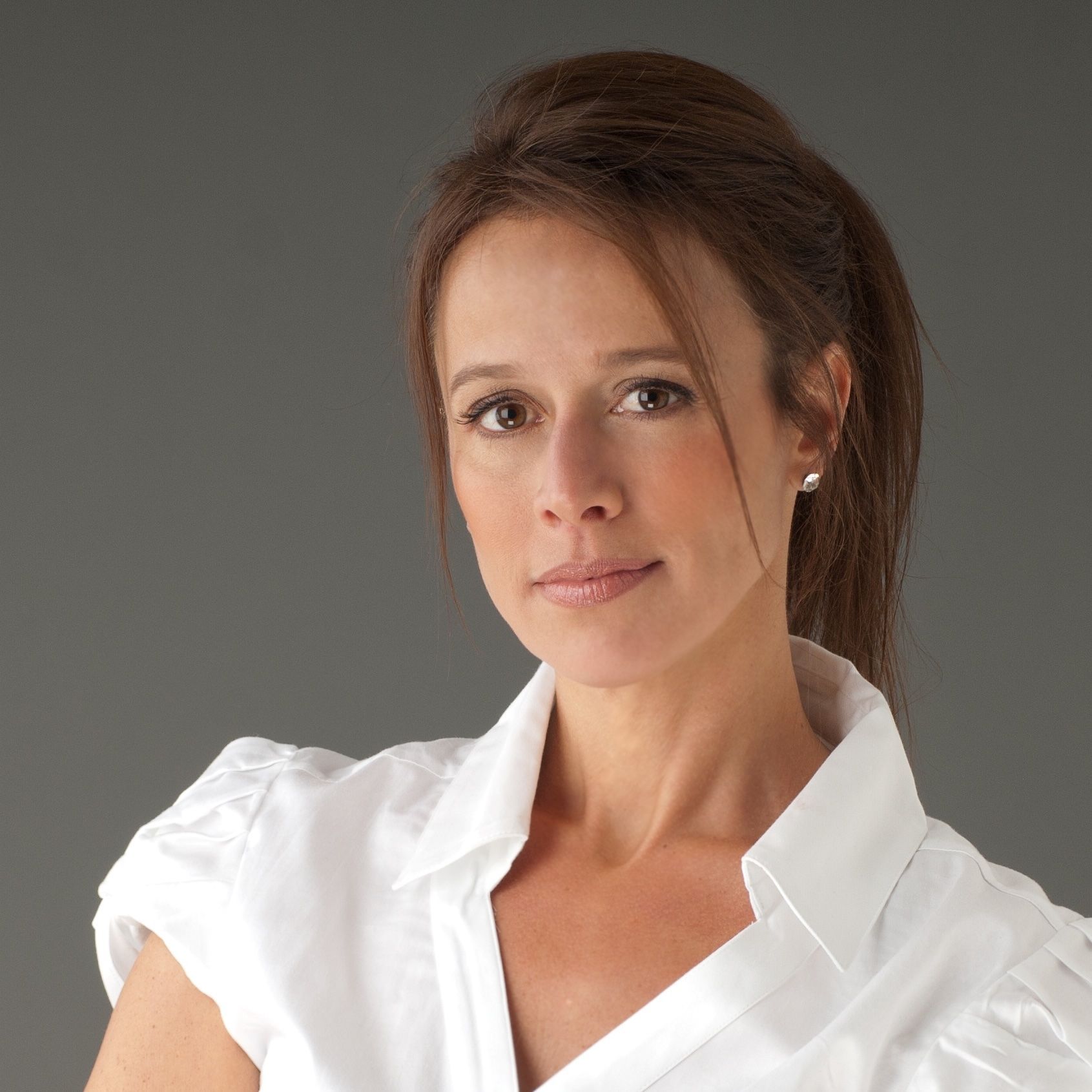 Woman with brown hair in a white blouse, looking at the camera.