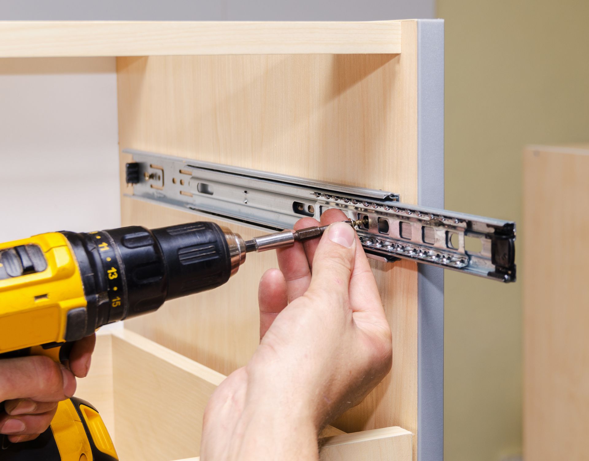 A Person Is Using A Drill To Install Drawer Slides On A Cabinet - Drumore, PA - Tanglewood Lawn Service