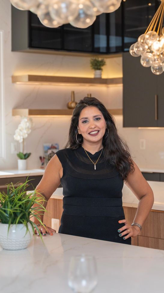 A woman is sitting at a desk with a laptop and a vase of flowers.