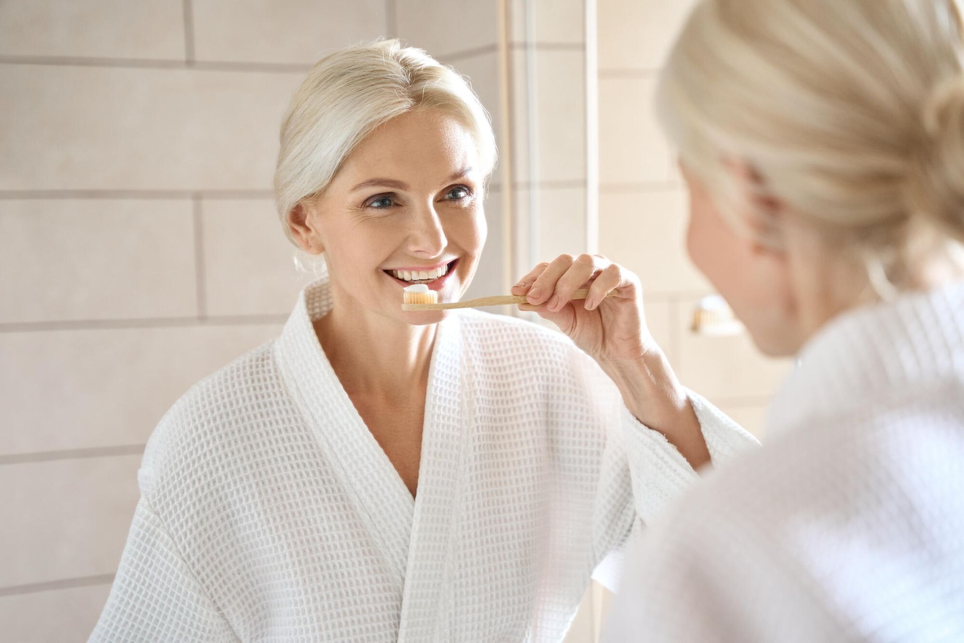 A woman is brushing her teeth in front of a mirror.