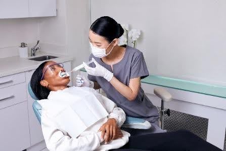 Dentist treating a patient in a dental office. The patient has a dental dam in place.