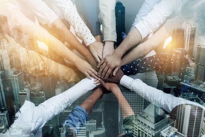 Shot of a group of businesspeople joining hands in solidarity