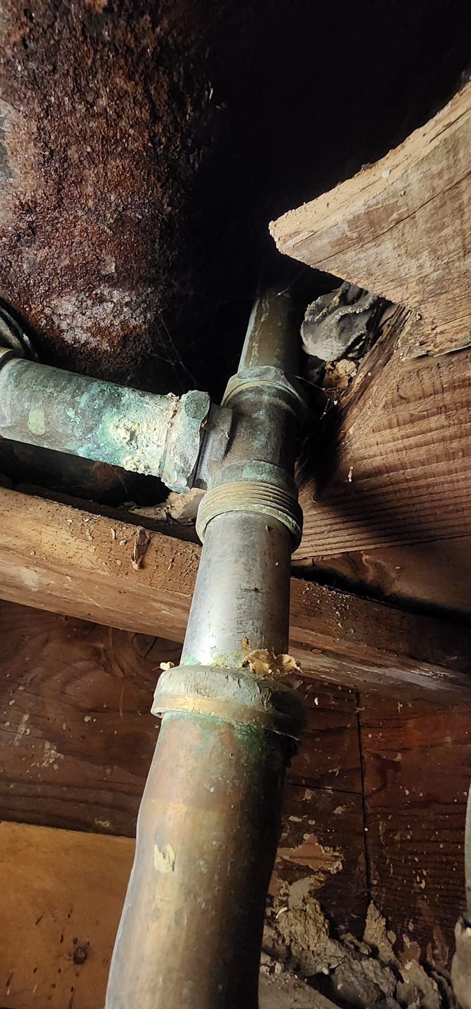 A close up of a rusty pipe in a wooden room.