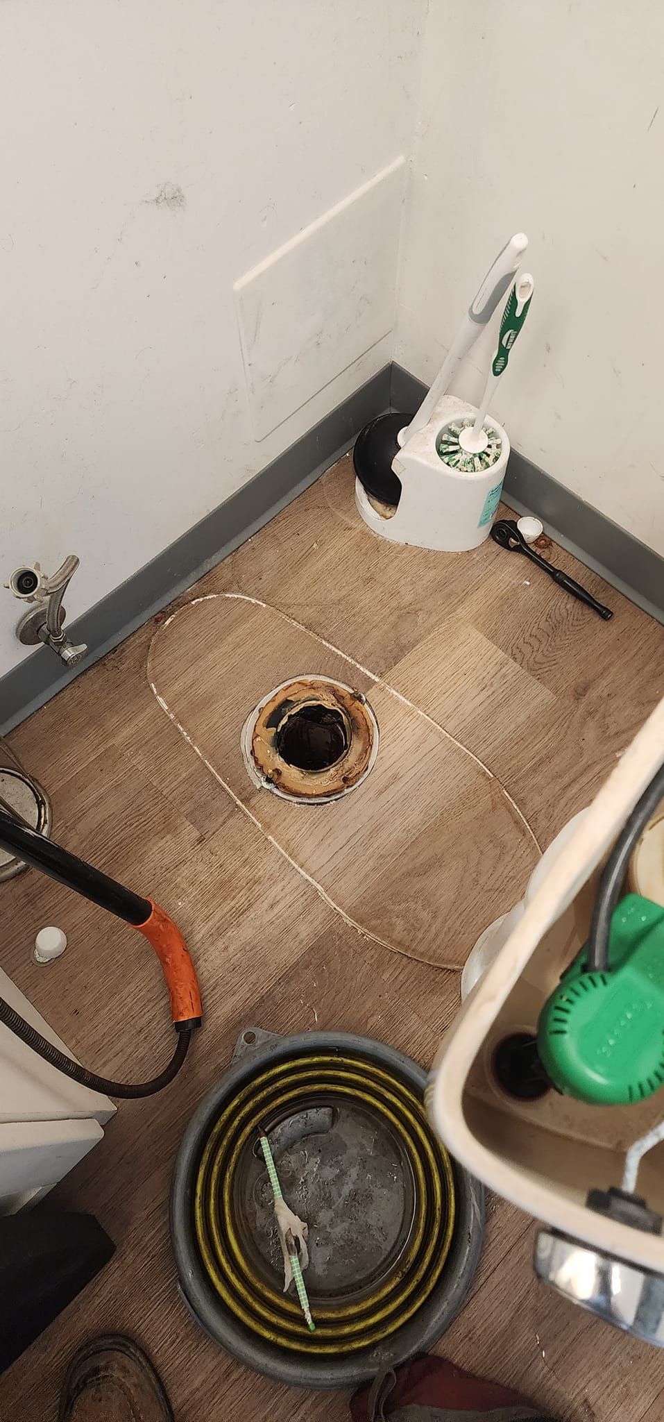A bathroom with a hole in the floor and a toilet.