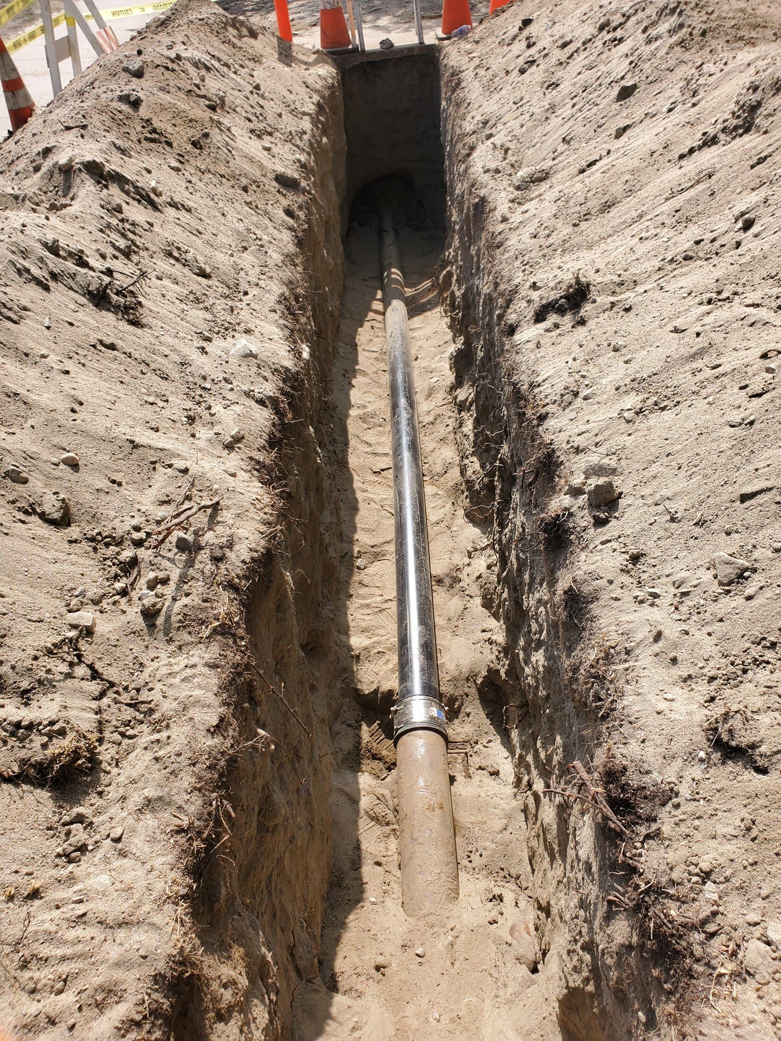 A pipe is being installed in a trench in the dirt.