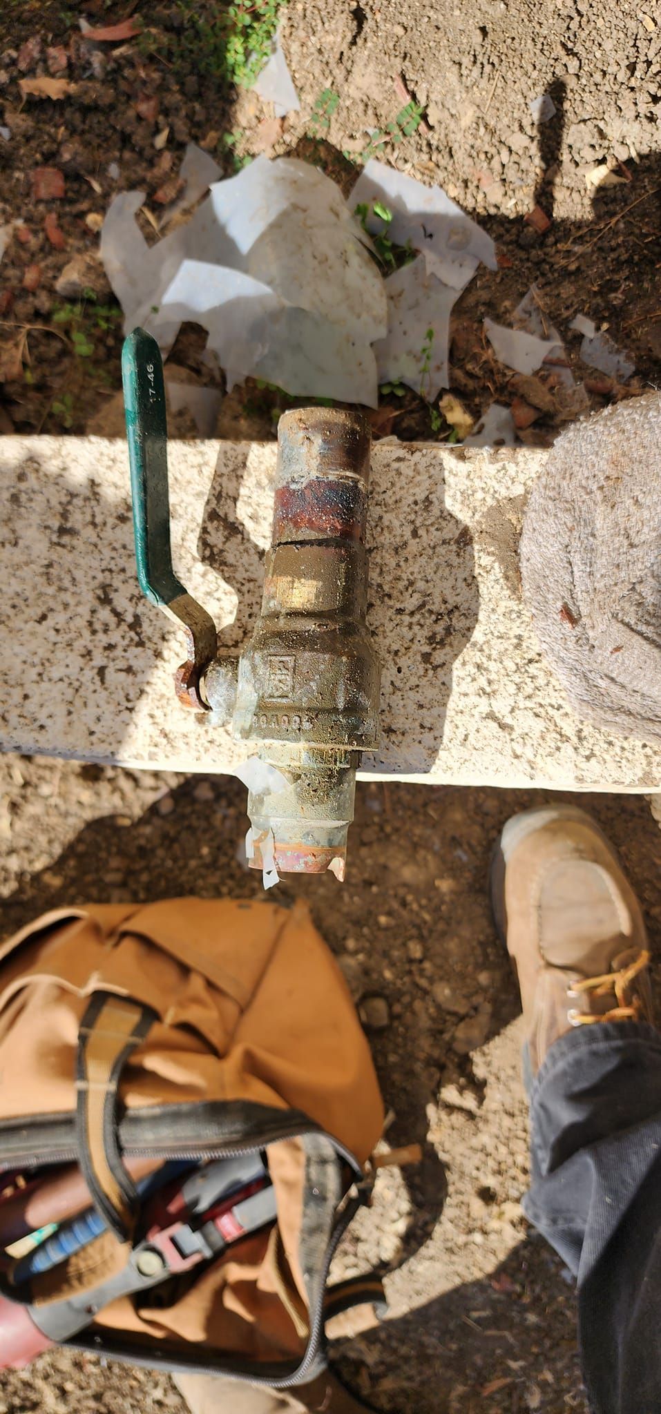 A person is standing next to a bottle of water and a backpack.