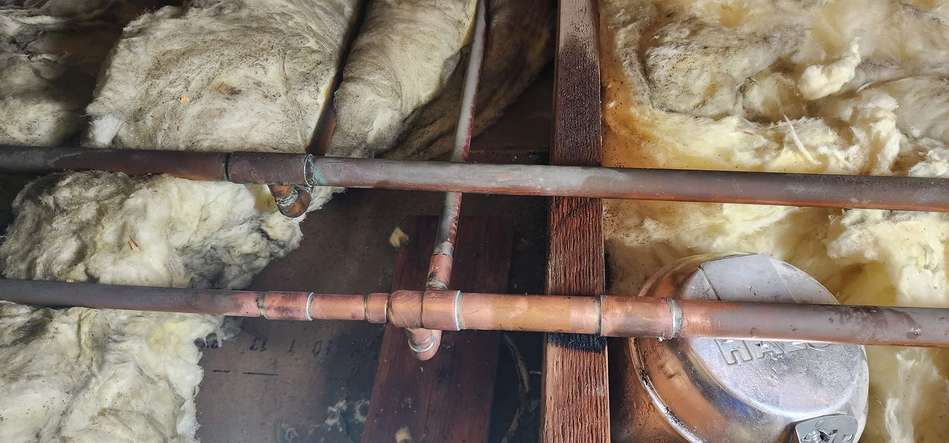 A close up of a copper pipe in a wall.