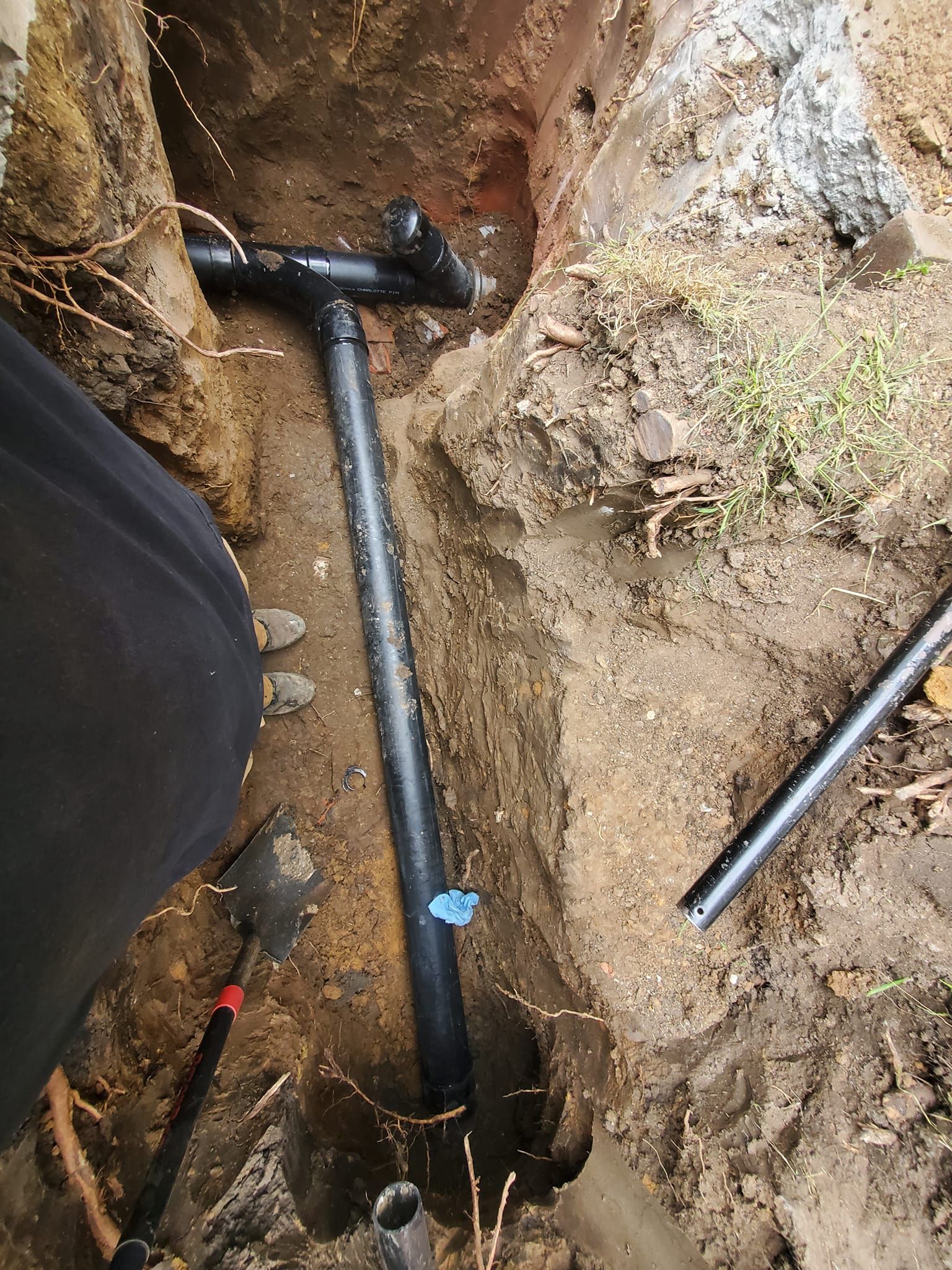A person is working on a pipe in the dirt.