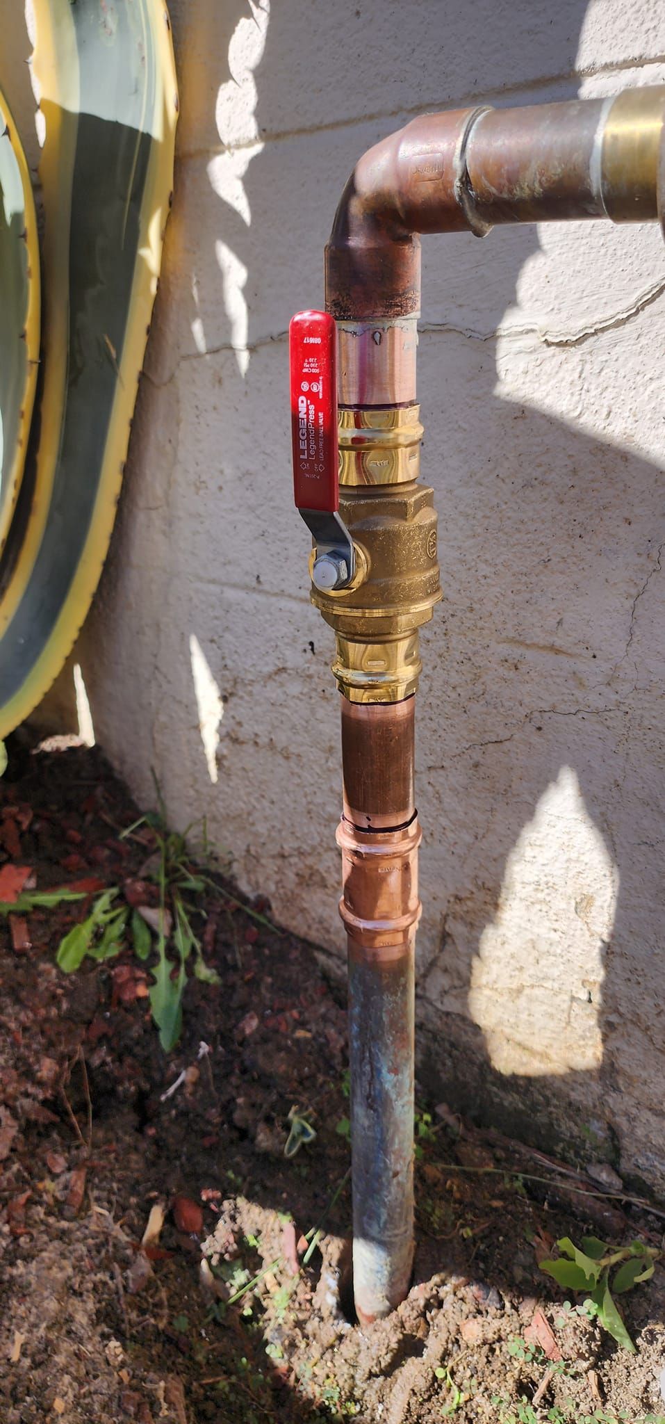 A close up of a copper pipe with a red valve on it.