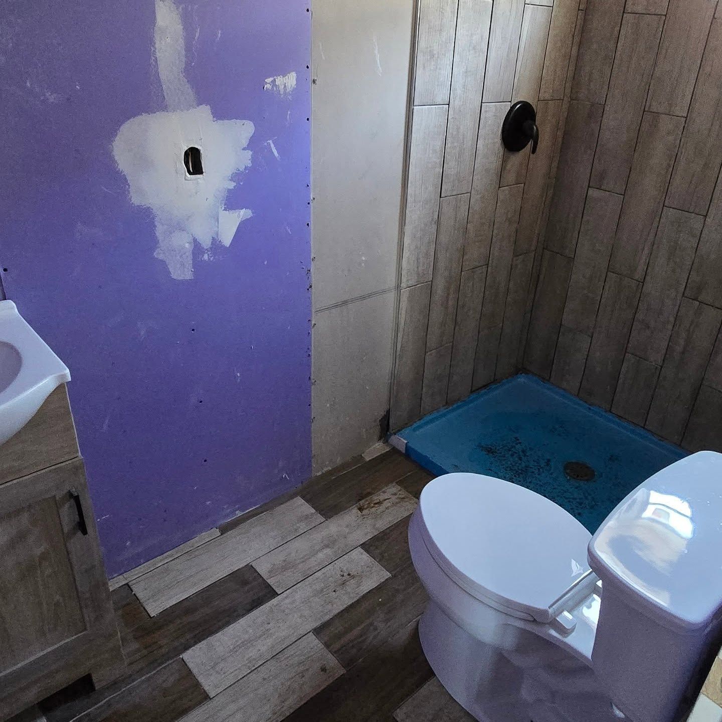 A bathroom with a toilet a sink and a purple wall