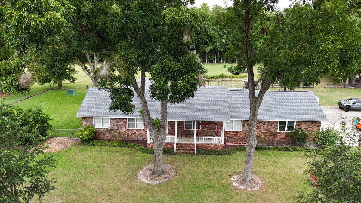 An aerial view of a brick house surrounded by trees and grass.