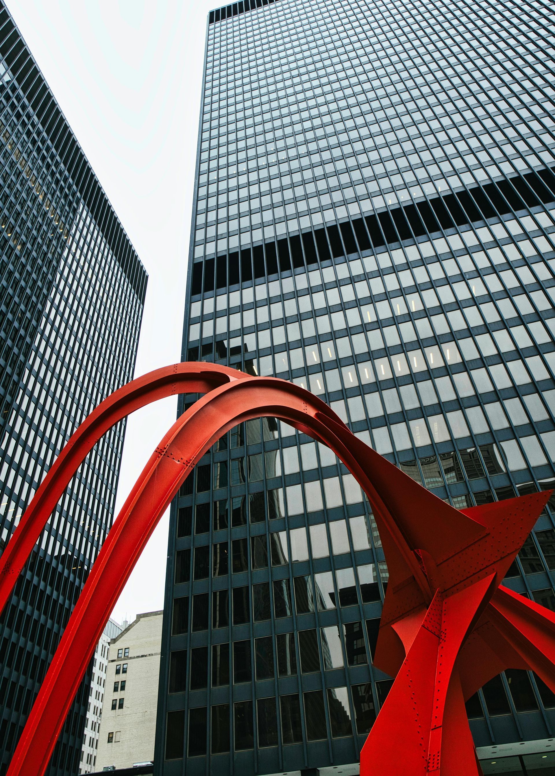 A red sculpture in front of a tall building