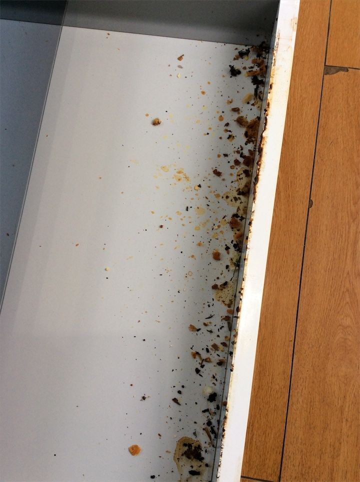 Food debris inside kitchen drawer beneath oven – check-out inspection photo