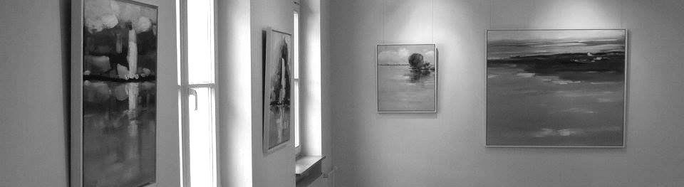 Ein Schwarzweißfoto eines Flurs mit Gemälden an der Wand.