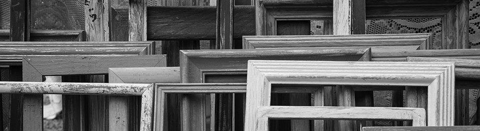 Ein Schwarzweißfoto von mehreren übereinander gestapelten Bilderrahmen.