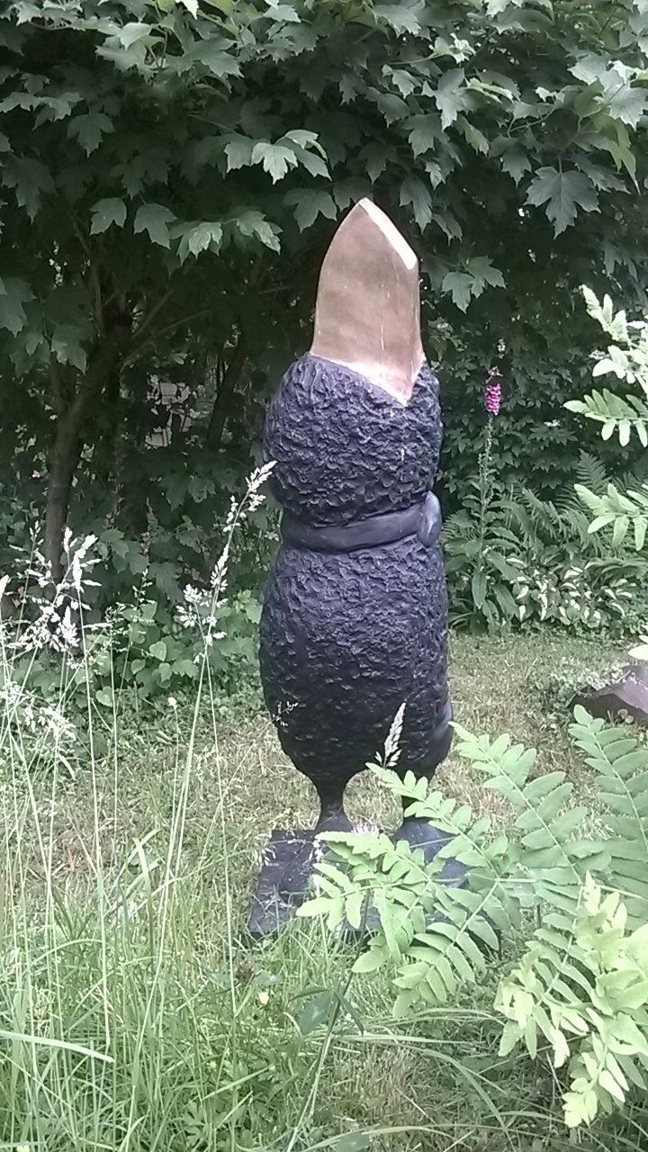 Eine Pinguinstatue steht im Gras in einem Garten.