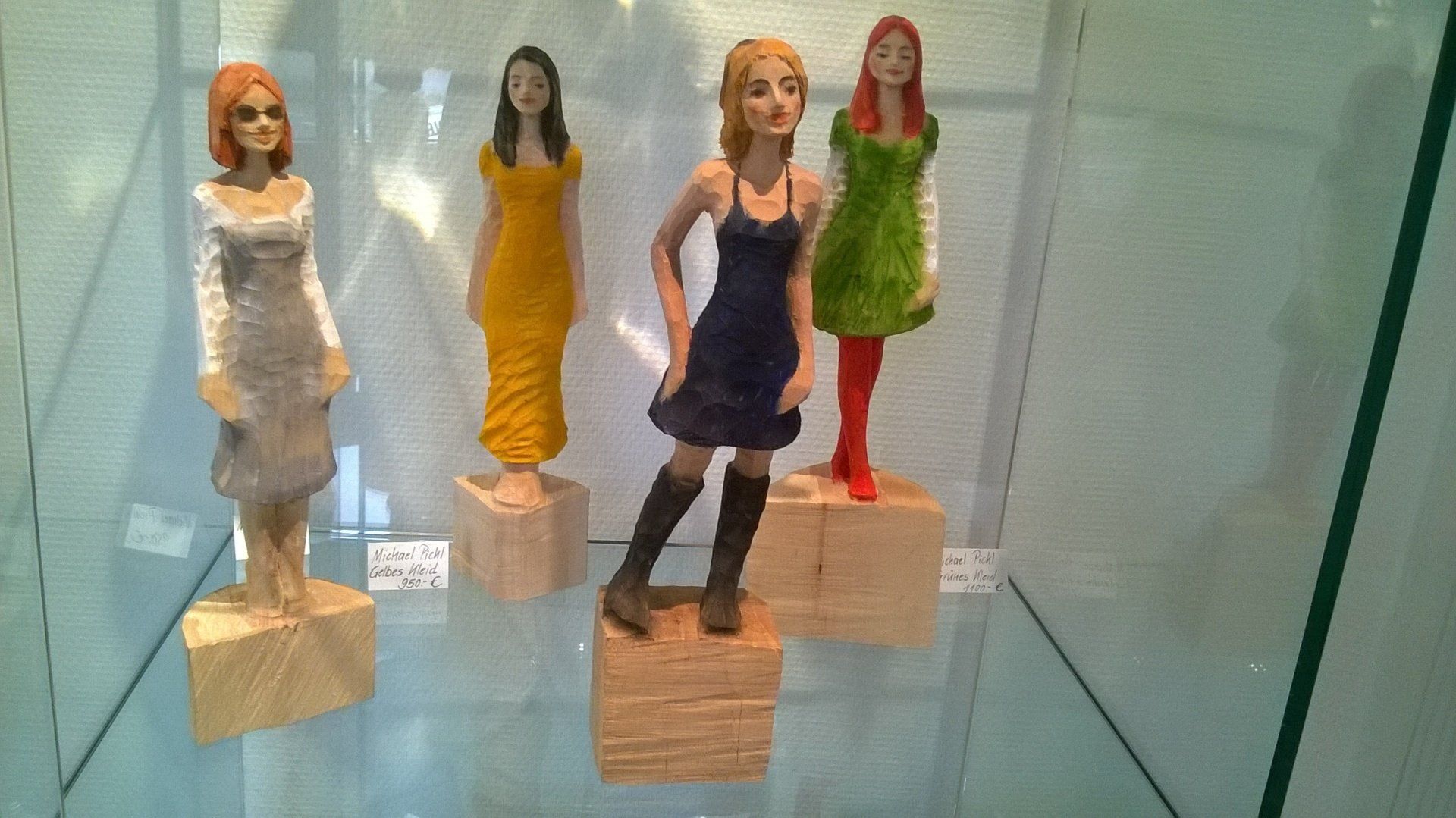 In einer Glasvitrine sind vier Frauenfiguren ausgestellt