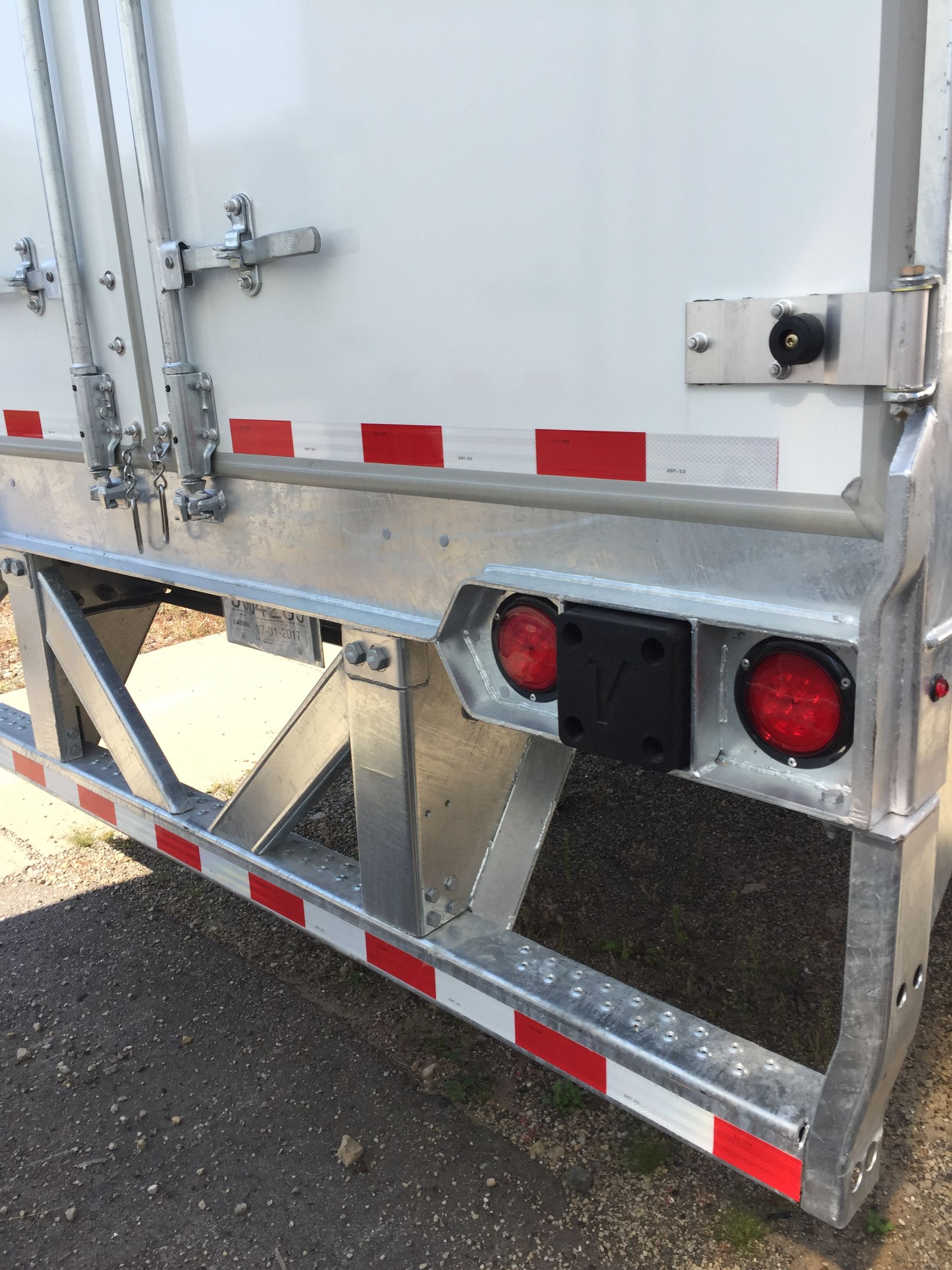 A white truck with red and white stripes is parked on the side of the road.