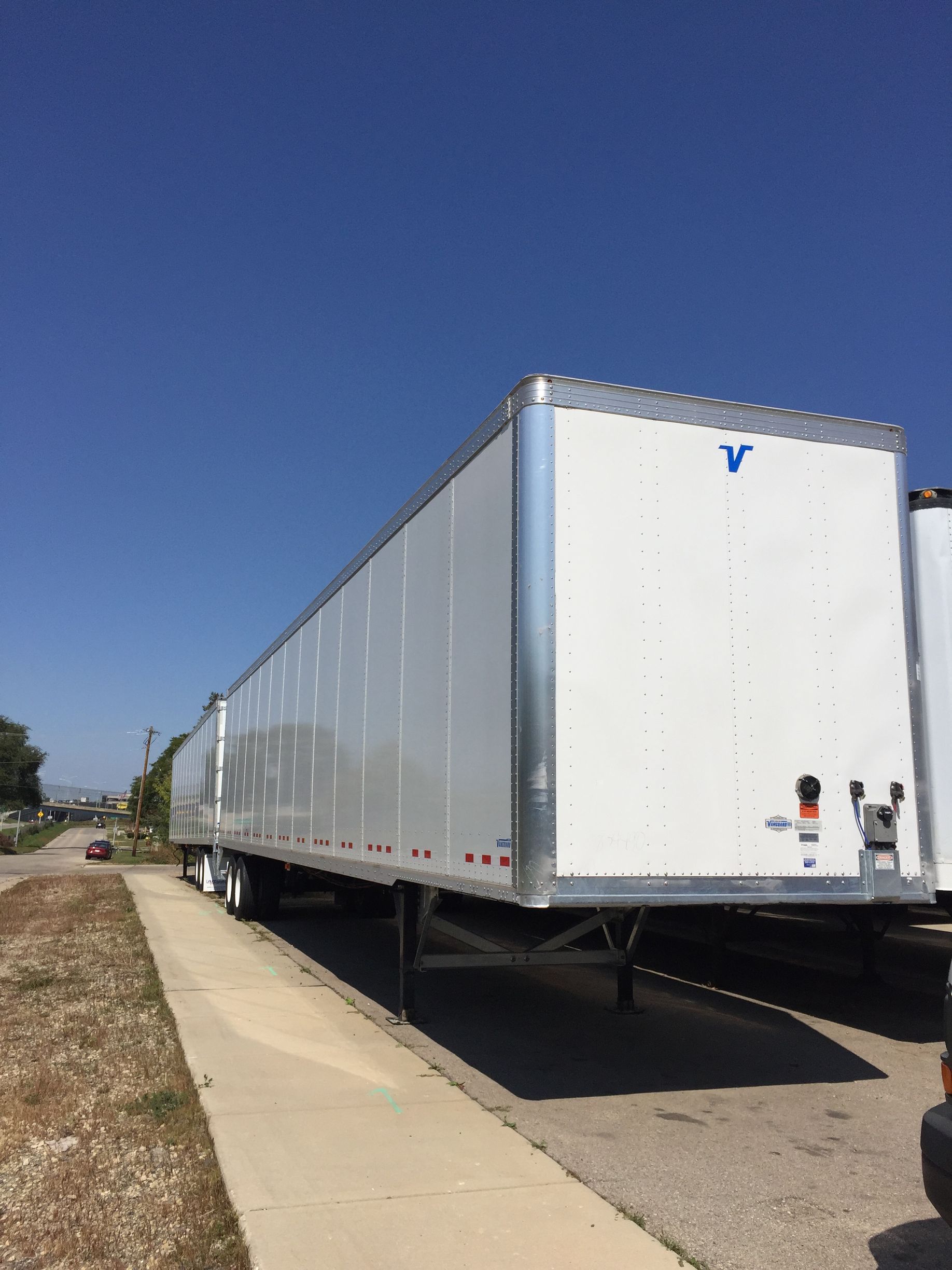 A white trailer is parked on the side of the road.