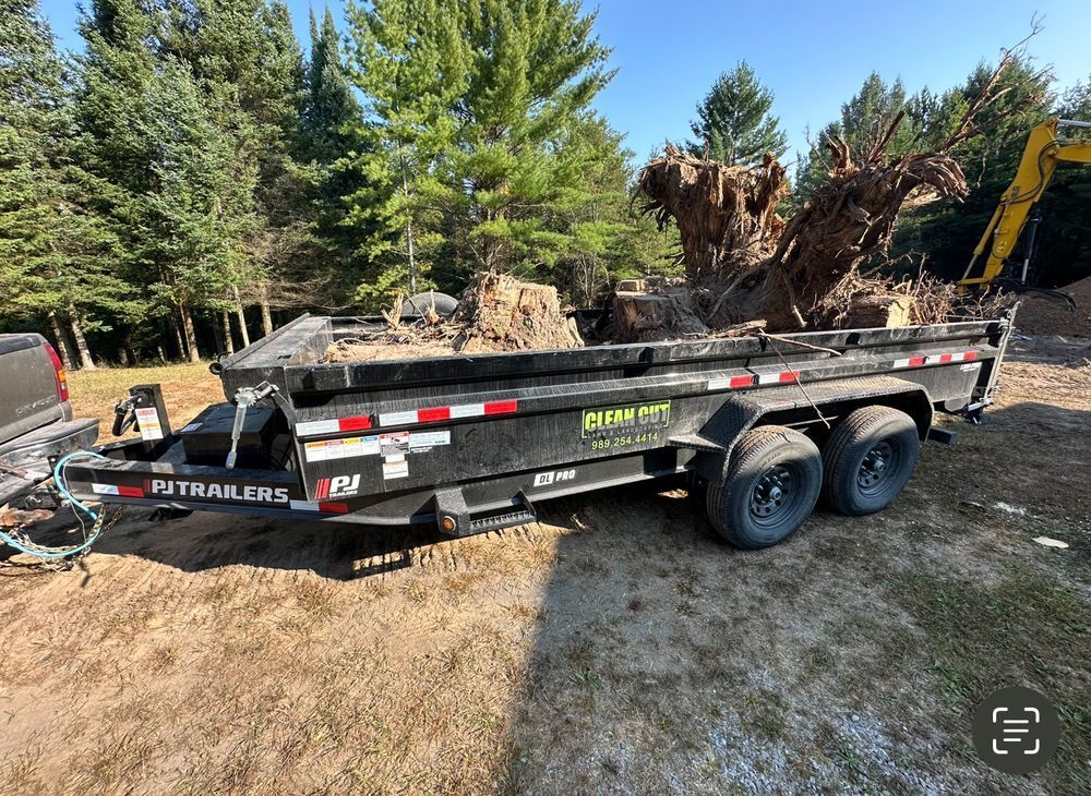 A dumpster trailer is parked in a dirt lot next to a truck.