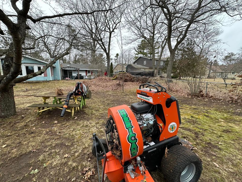 An orange lawn mower is parked in a yard next to a picnic table.