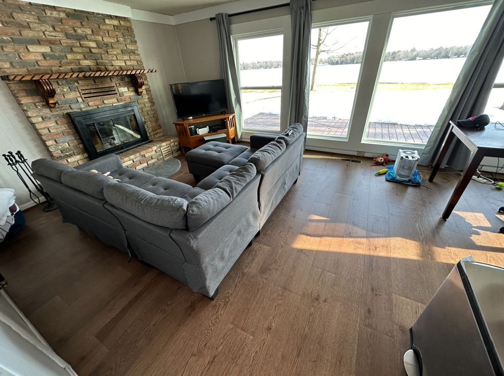 A living room with a couch , fireplace , television and lots of windows.