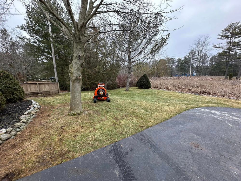 A lawn mower is parked in a grassy yard next to a tree.