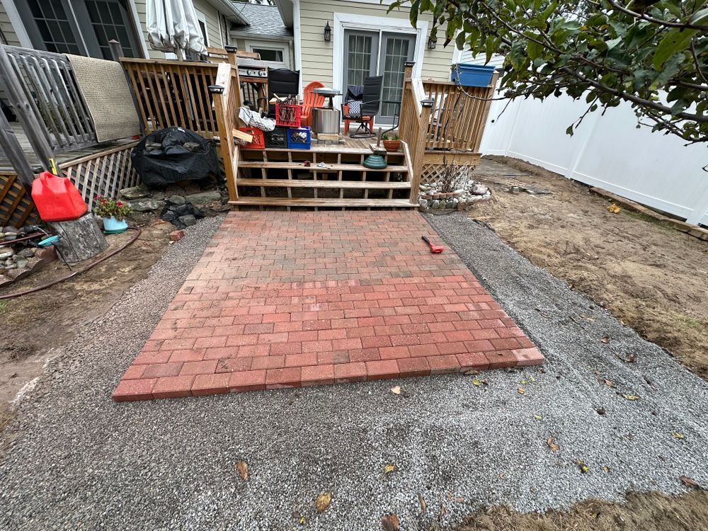 A brick walkway is being built in the backyard of a house.
