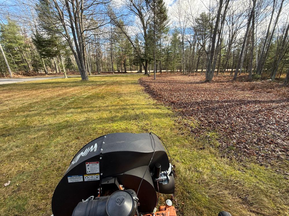 A leaf blower is blowing leaves in a park.