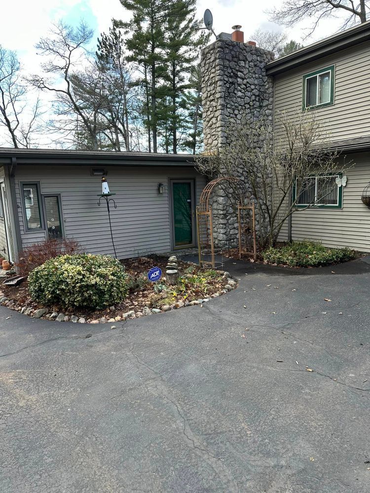 A large house with a stone chimney and a driveway in front of it.