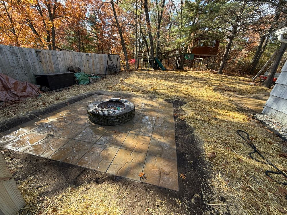A fire pit is sitting in the middle of a backyard surrounded by trees.