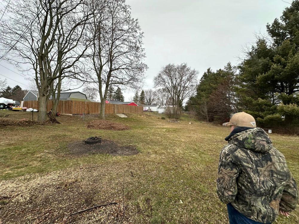 A man in a camouflage jacket is standing in a grassy field.